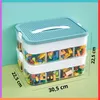 A two-tiered storage container filled with colorful building blocks. Produktbild-Vorschau