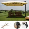 A large cream-colored cantilever umbrella is set up on a grassy lawn, providing shade for outdoor furniture. The background shows a rolling landscape with trees and houses under a partly cloudy sky. Smaller inset images show details of the umbrella's mecha Produktbild-Vorschau