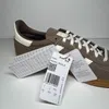 A close-up view of a brown Adidas Handball Spezial W sneaker with its tags attached. Voir les images du produit