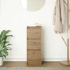 A narrow wooden cabinet with three drawers sits against a white wall, next to a potted plant and a coat rack with a coat and bag. Produktbild-Vorschau