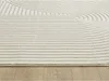 A close-up view of a cream-colored rug with a geometric pattern, placed on a wooden floor. Produktbild-Vorschau