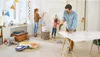 A family is painting a wall in a room with toys scattered around. Podgląd zdjęcia produktu