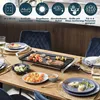 A table set for a meal with an electric grill in the center, surrounded by plates of food and chairs. Voir les images du produit