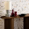 A console table with decorative items against a terrazzo-patterned wall. Produktbild-Vorschau