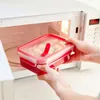 A person is placing a red food container into a microwave. Produktbild-Vorschau
