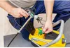 A person is using a paint sprayer connected to a yellow machine. Náhled obrázku produktu