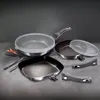 A set of cookware, including frying pans and detachable handles, arranged on a textured surface. Náhled obrázku produktu