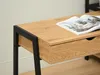 A close-up view of a desk with a wooden top and black metal legs, showing a drawer and an open magazine. Produktbild-Vorschau