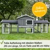 A grey wooden rabbit hutch with two attached runs, set up on a green lawn with trees in the background. Produktbild-Vorschau