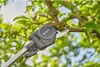 A close-up of a Gardena telescopic tree pruner cutting a branch on a tree. Produktbild-Vorschau