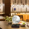 A levitating moon lamp is displayed on a table in a restaurant setting. Náhled obrázku produktu