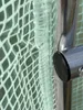 Close-up of a green plastic mesh material attached to a silver metal pole with a black cap. Produktbild-Vorschau