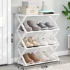 A white, multi-tiered shoe rack filled with various shoes, placed against a light gray wall next to a doorway. Anteprima dell’immagine prodotto