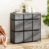 A gray fabric dresser with nine drawers is placed against a white wall, with decorative items on top. Anteprima dell’immagine prodotto