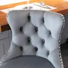 Close-up of a tufted gray velvet bar stool with silver nailhead trim, placed at a kitchen island. Produktbild-Vorschau