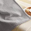 A close-up of a gray blanket with a chevron pattern draped over a sofa. Anteprima dell’immagine prodotto