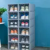 A stack of clear plastic shoe boxes filled with various shoes against a blue background. Produktbild-Vorschau