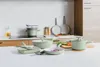 A collection of green cookware items arranged on a kitchen countertop and stovetop. Anteprima dell’immagine prodotto