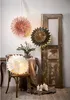 A decorative scene with hanging paper stars, a chair with a lit paper star, a vase of greenery, and candles. Podgląd zdjęcia produktu