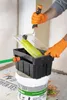 A person wearing orange gloves is using a paint roller to clean it in a specialized washing device. Náhled obrázku produktu