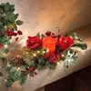 A festive Christmas garland with a candle, flowers, and ornaments on a mantelpiece. Produktbild-Vorschau