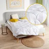A bed with a white comforter and yellow pillows, in a bedroom setting. Produktbild-Vorschau
