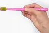 A hand holding a pink toothbrush with green bristles. Náhled obrázku produktu