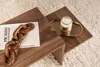 A close-up view of a wooden coffee table with decorative items on it, placed on a fluffy rug. Náhľad obrázku produktu