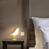 A bird-shaped lamp on a nightstand next to a bed. Anteprima dell’immagine prodotto