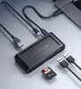 A black docking station with multiple ports, connected to a laptop via USB-C, with USB cables and an SD card nearby. Produktbild-Vorschau