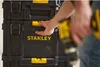 A person is shown interacting with a stack of Stanley toolboxes, holding a power drill. Voir les images du produit