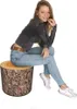 A young woman is sitting on a log-shaped pouf. Podgląd zdjęcia produktu