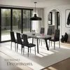 A dining room set with a table and chairs, illuminated by a pendant light, with large windows showing a garden view. Náhled obrázku produktu