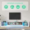 A white TV stand with LED lighting, featuring various decorative items and storage compartments, with a large black TV mounted on the wall above it. Produktbild-Vorschau