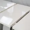 Close-up view of a white high-gloss table surface, showing the extension mechanism. Produktbild-Vorschau