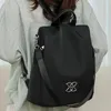 Schwarzer Rucksack mit silbernem ineinandergreifendem Schlaufenemblem auf der Vorderseite, auf dem Rücken einer Person getragen Produktbild-Vorschau