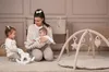A mother is playing with her two young children on a play mat. Produktbild-Vorschau