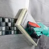 A gloved hand is using a trowel with a sponge attachment to apply grout to a tiled wall. Produktbild-Vorschau