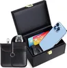 A black carbon fiber textured box with a gold latch is open, revealing credit cards, a car key, and a smartphone inside. A separate black carbon fiber pouch with a key ring is positioned to the left. Produktbild-Vorschau