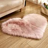 A pink heart-shaped rug on a wooden floor next to a sofa. Produktbild-Vorschau