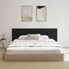 A bed with a black headboard and beige frame, dressed with white bedding and a decorative pillow. Anteprima dell’immagine prodotto