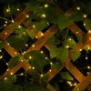 A string of micro LED lights is wrapped around a wooden lattice covered in green leaves. Produktbild-Vorschau