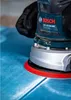 A person is using a Bosch sander on a blue surface. Náhľad obrázku produktu