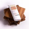 A tube of GUINOT Crème Youth Perfect Finish cream is placed on a stack of wooden coasters against a striped background. Produktbild-Vorschau