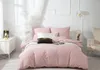 A neatly made bed with pink bedding and decorative pillows in a bright, minimalist room. Podgląd zdjęcia produktu