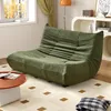 A green sofa is placed in a living room setting with a coffee table and a rug. Produktbild-Vorschau