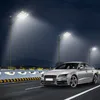A silver car drives on a road at night, illuminated by streetlights. Voir les images du produit