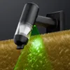 A close-up of a black handheld vacuum cleaner with a green light beam illuminating dust particles on a fuzzy brown surface. Podgląd zdjęcia produktu
