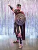 A man dressed in a gladiator costume stands in front of a shimmering silver curtain. Podgląd zdjęcia produktu