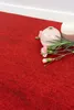 A close-up shot of red carpet tiles with two decorative vases and pink flowers. Produktbild-Vorschau